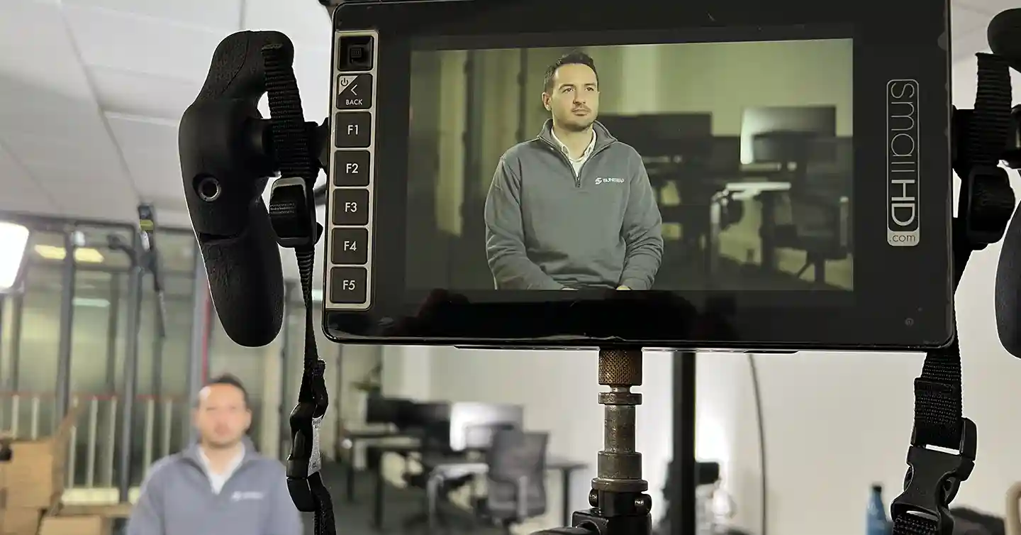 Still image from behind the scenes of filming a startup video. Shows a monitor with a guy being interviewed in an office.