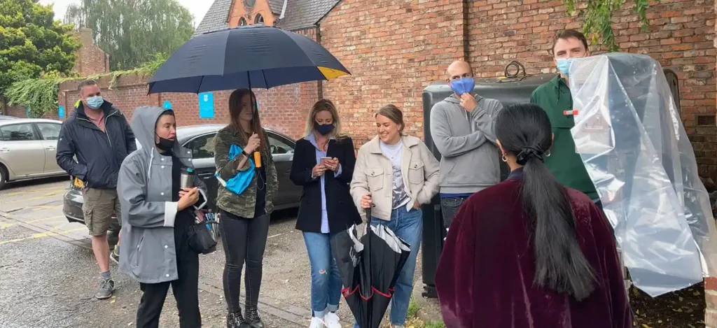 A TV Commercial Production crew filming in Manchester. A group of people standing around a monitor in the rain.