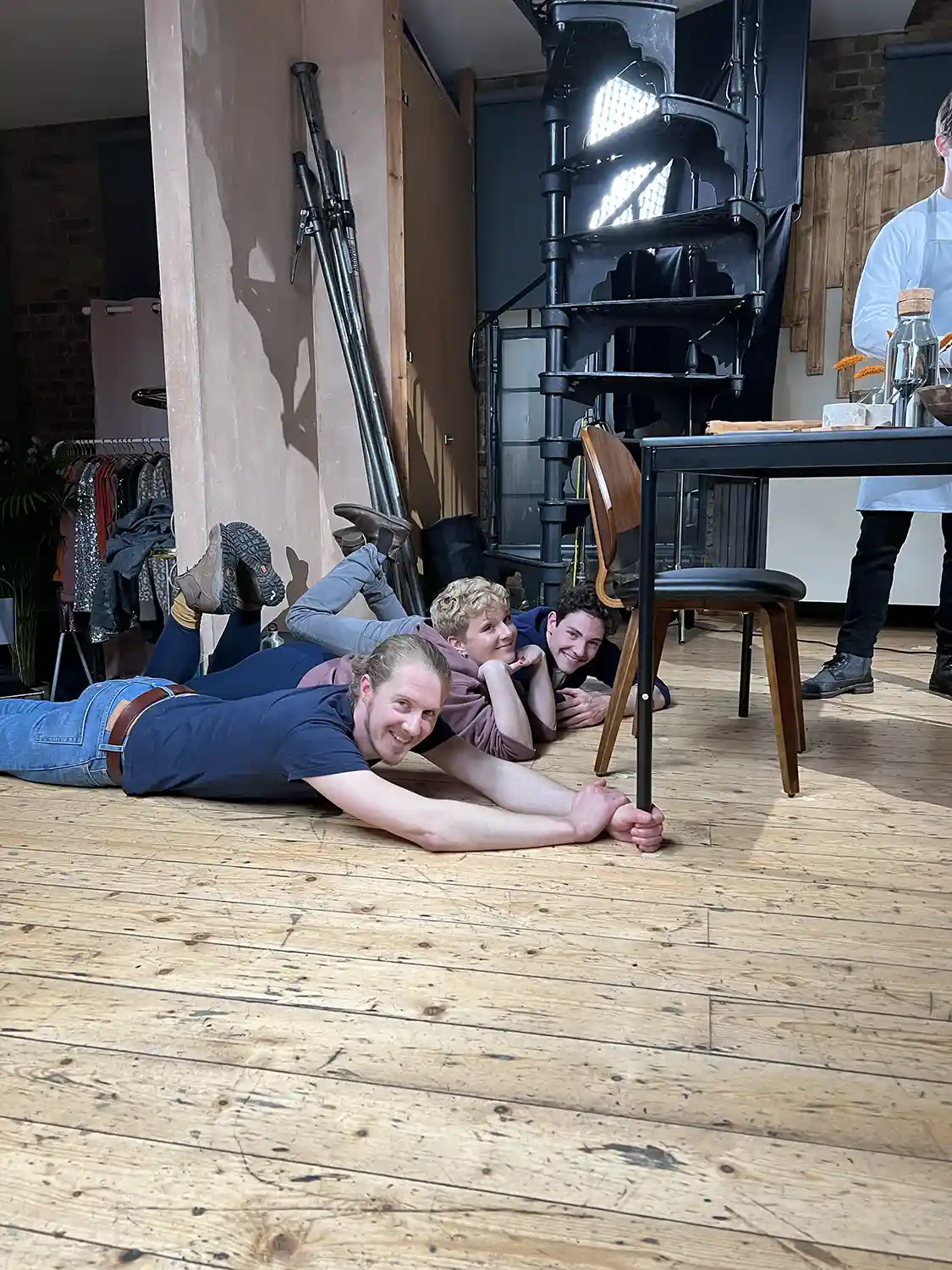 image from the set of a startup video production. 3 people are laying on the floor so they can move furniture so it looks like it's moving magically.
