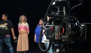 A Sony camera in the foreground, with cast in the background, at a film studio.