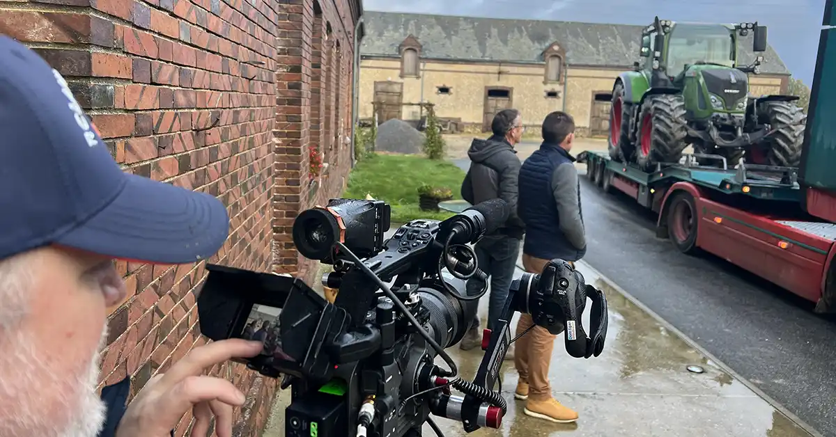 A man filming branded content with 2 farmers and a tractor on a truck