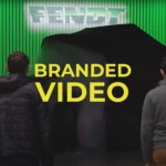 Branded video production featured image features two men watching a refurbished tractor about to be revealed