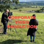 A man and a woman standing in a beautiful green field filming a corporate video.
